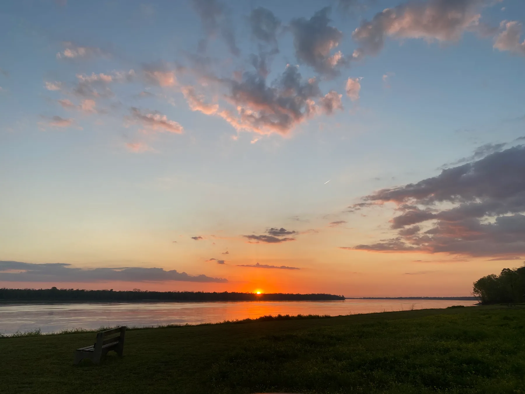 A bench facing the river at sunset